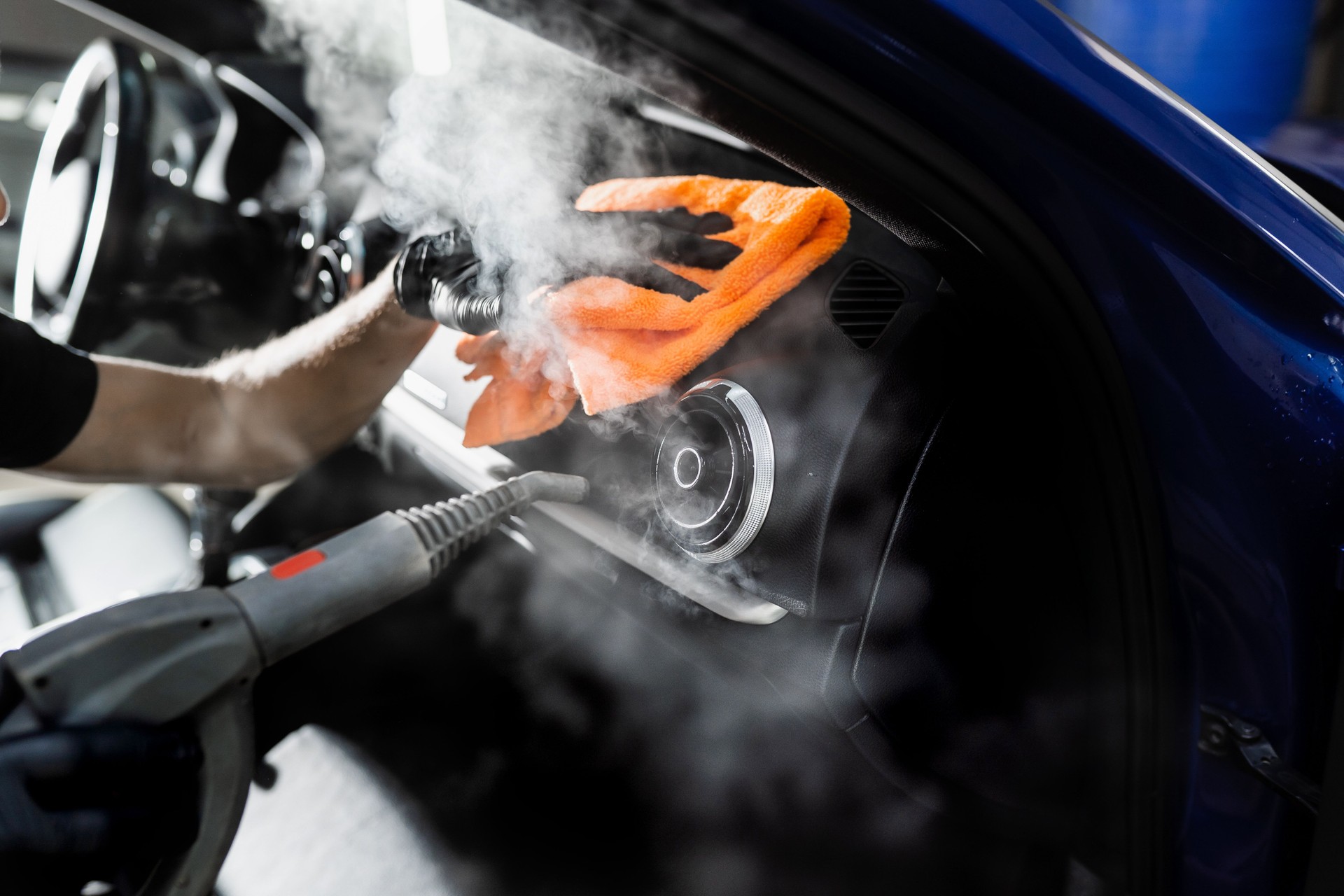 Steam cleaning of car air system. Worker in auto cleaning service clean car inside. Car interior detailing.